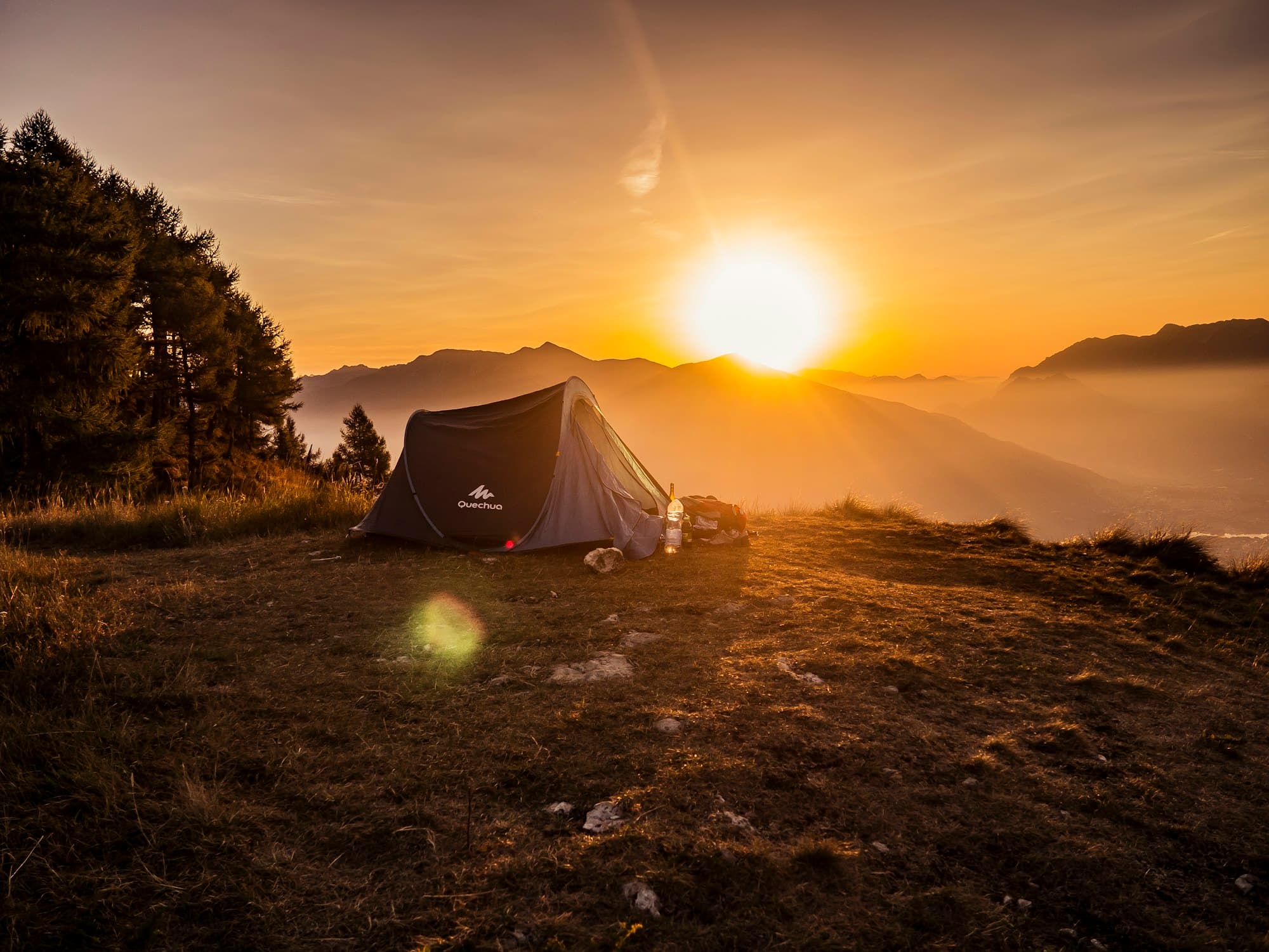 Tented camp glowing at sunrise over golden hills